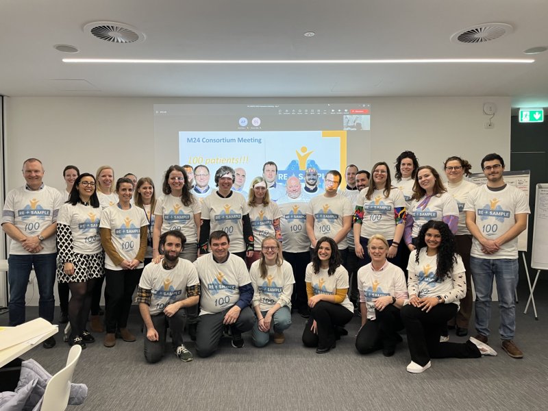 Group picture of the RE-SAMPLE Consortium from March 2023. Participants are wearing t-shirts with project logo and number 100 to mark the enrollment of the 100th patient in the project.